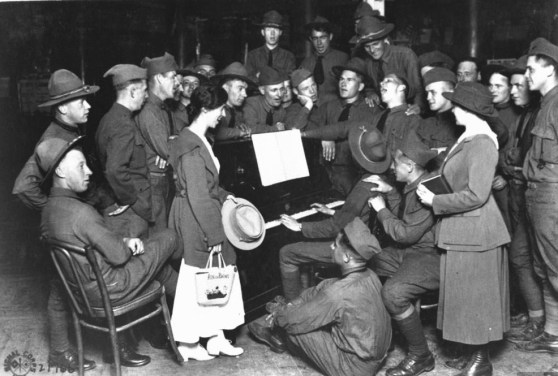 us-soldiers-and-ymca-girls-gathered-around-a-piano-player-and-enjoying-a-sing-along-during-leisure-time-from-wwi-aix-le-bains-france-august-1918
